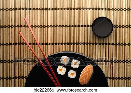 Stock Photography - Chopsticks and sushi on round plate with dipping sauce. Fotosearch