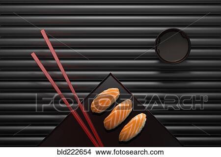 Picture - Chopsticks and sushi on square plate with dipping sauce. Fotosearch