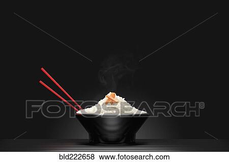 Chopsticks in bowl of steaming white rice View Large Photo Image Stock Photo - Chopsticks in bowl of steaming white rice. Fotosearch