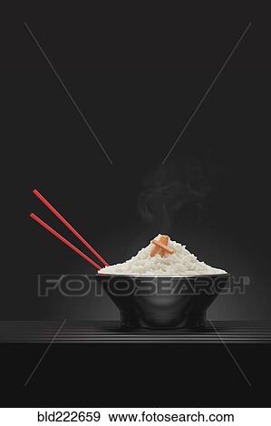 Stock Photo - Chopsticks in bowl of steaming white rice. Fotosearch