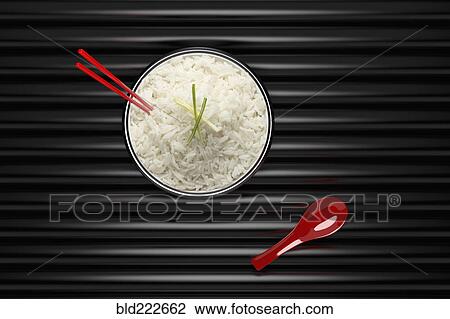 Stock Image - Chopsticks in bowl of white rice with red spoon. Fotosearch
