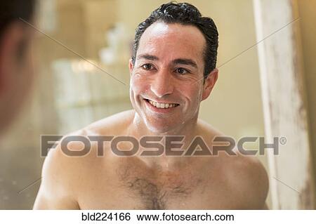 Stock Photograph - Clean-shaven Hispanic man smiling in mirror. Fotosearch