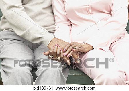 Stock Image - Close up of African couple holding hands. Fotosearch