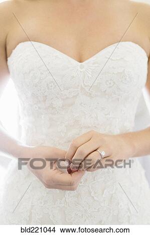 Picture - Close up of bride wearing wedding dress and engagement ring. Fotosearch
