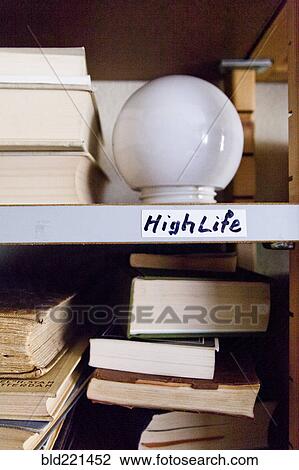 Stock Image - Close up of light bulb on shelf with books. Fotosearch