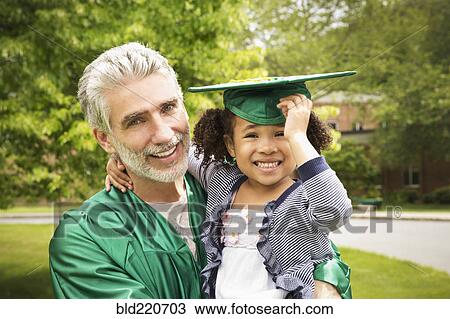 Stock Image - College graduate father holding daughter. Fotosearch