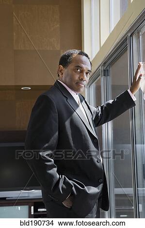 Confident African businessman leaning on glass door View Large Photo Image Picture - Confident African businessman leaning on glass door. Fotosearch