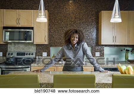 Stock Photo - Confident African woman standing in modern kitchen. Fotosearch