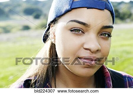 Stock Photo - Confident Mixed Race woman wearing backward baseball cap. Fotosearch