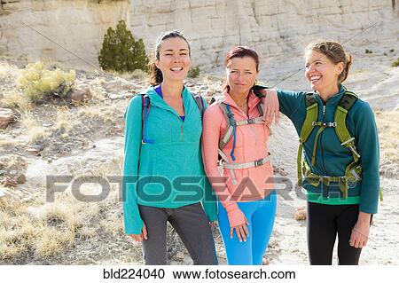 Stock Image - Confident women standing in canyon wearing backpacks. Fotosearch