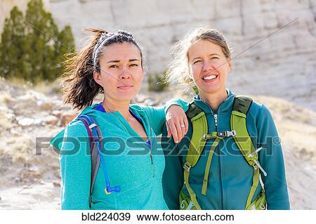 Stock Photo - Confident women standing in canyon wearing backpacks. Fotosearch