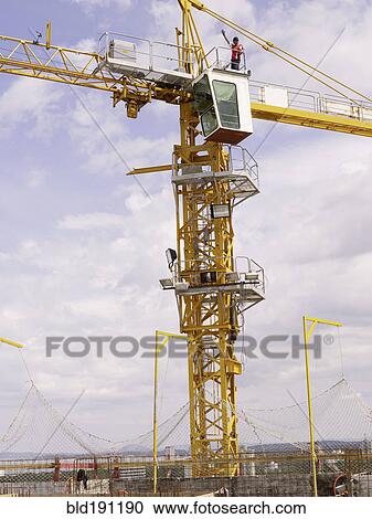 Stock Image - Construction worker on top of crane. Fotosearch