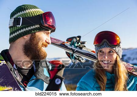 Stock Photography - Couple carrying skis on snowy mountain. Fotosearch