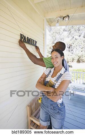 Couple hanging family sign on house View Large Photo Image Stock Photography - Couple hanging family sign on house. Fotosearch