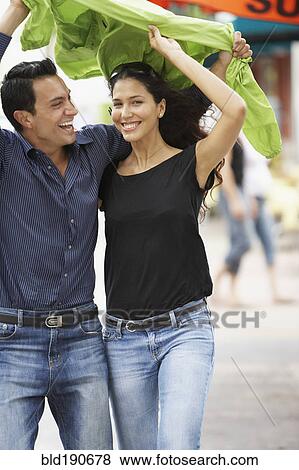 Stock Photo - Couple holding raincoat over heads. Fotosearch