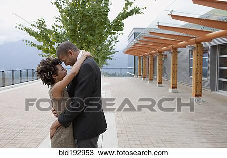 Stock Image - Couple hugging in courtyard. Fotosearch