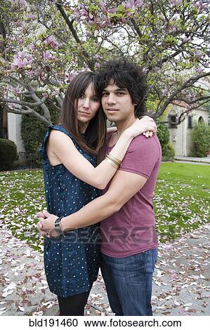 Stock Image - Couple hugging near tree with spring blossoms. Fotosearch