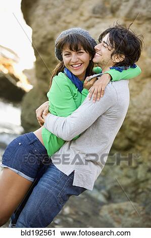 Stock Image - Couple hugging on beach. Fotosearch