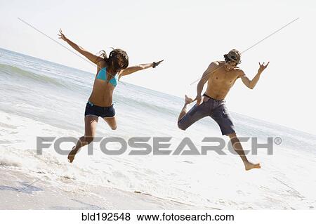 Couple jumping on beach together View Large Photo Image Stock Photo - Couple jumping on beach together. Fotosearch