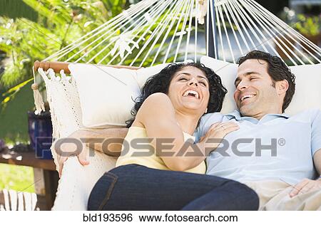 Stock Photograph - Couple laughing and laying in hammock. Fotosearch