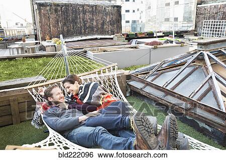 Stock Photograph - Couple laying in hammock on urban rooftop. Fotosearch