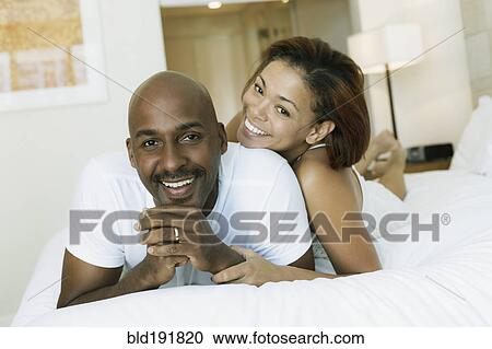 Stock Image - Couple laying on bed. Fotosearch