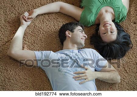 Picture - Couple laying on floor holding hands. Fotosearch