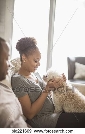 Stock Photo - Couple petting dog on sofa. Fotosearch