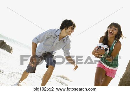 Stock Image - Couple playing with soccer ball on beach. Fotosearch