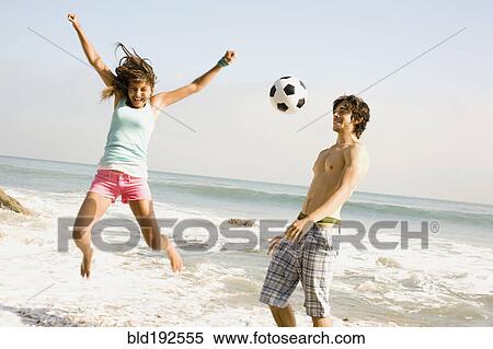 Stock Photography - Couple playing with soccer ball on beach. Fotosearch