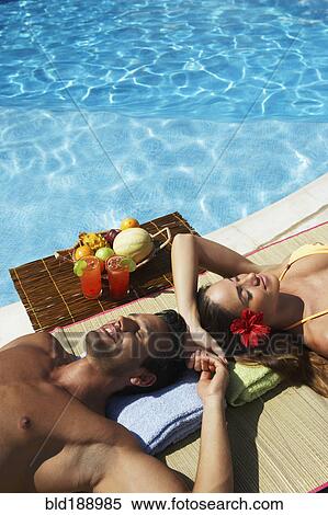 Stock Photography - Couple relaxing at edge of swimming pool. Fotosearch