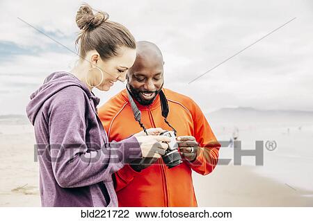 Couple reviewing digital photographs on beach View Large Photo Image Stock Image - Couple reviewing digital photographs on beach. Fotosearch