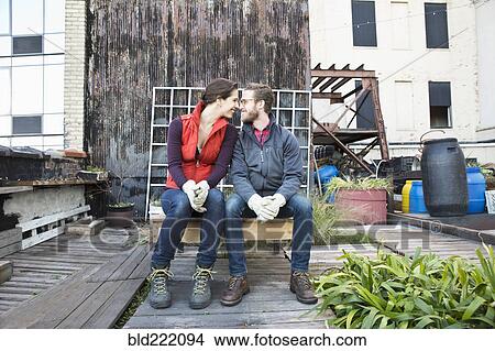 Picture - Couple sitting in urban rooftop garden. Fotosearch