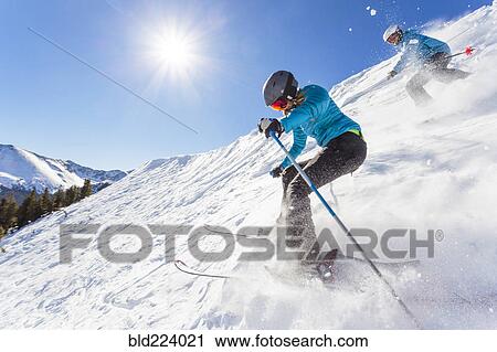 Stock Image - Couple skiing on snowy mountain slope. Fotosearch