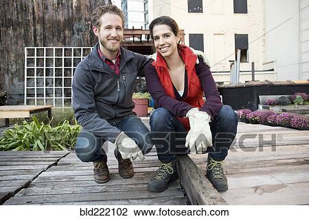 Couple smiling in urban rooftop garden View Large Photo Image Stock Image - Couple smiling in urban rooftop garden. Fotosearch