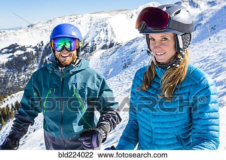 Stock Image - Couple standing on snowy mountaintop. Fotosearch