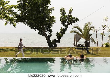 Couple swimming in luxury pool near ocean View Large Photo Image Stock Image - Couple swimming in luxury pool near ocean. Fotosearch