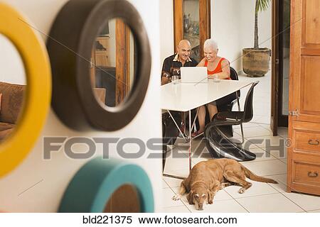 Stock Photography - Couple using laptop at table. Fotosearch