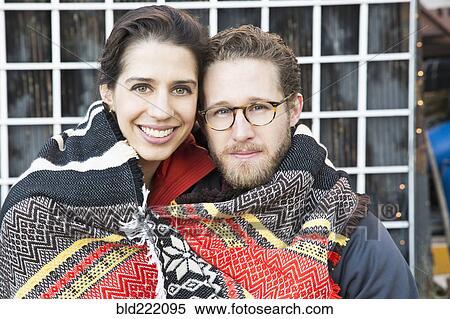 Stock Photography - Couple wrapped in blanket outdoors. Fotosearch