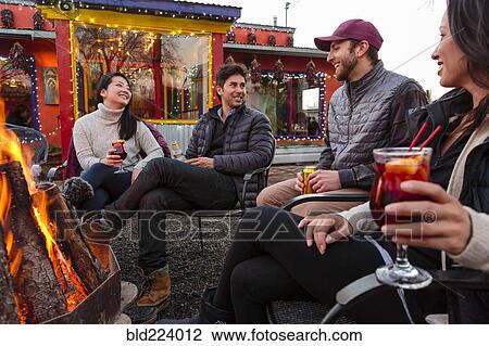 Couples drinking cocktails and beer outdoors at storefront campfire View Large Photo Image Stock Image - Couples drinking cocktails and beer outdoors at storefront campfire. Fotosearch