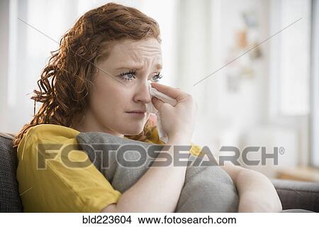 Picture - Crying Caucasian woman clutching pillow wiping tears. Fotosearch