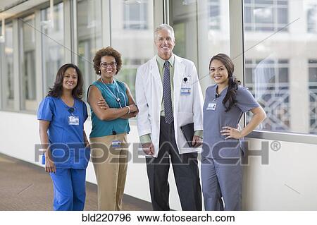 Stock Photograph - Doctor and nurses smiling in hospital hallway. Fotosearch