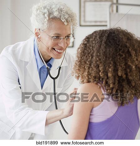 Stock Photo - Doctor checking girl's heart with stethoscope. Fotosearch