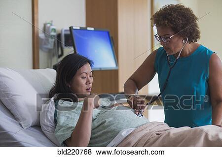 Stock Photo - Doctor listening to belly of pregnant patient. Fotosearch