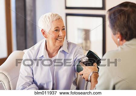 Stock Photo - Doctor taking woman's blood pressure. Fotosearch