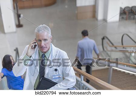 Picture - Doctor talking on cell phone on steps. Fotosearch