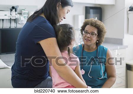 Stock Image - Doctor talking to mother and daughter in hotel room. Fotosearch