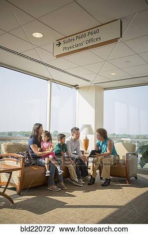 Stock Photo - Doctor talking to patients in waiting room. Fotosearch