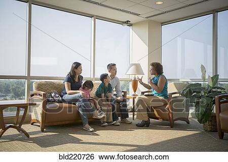 Stock Photograph - Doctor talking to patients in waiting room. Fotosearch