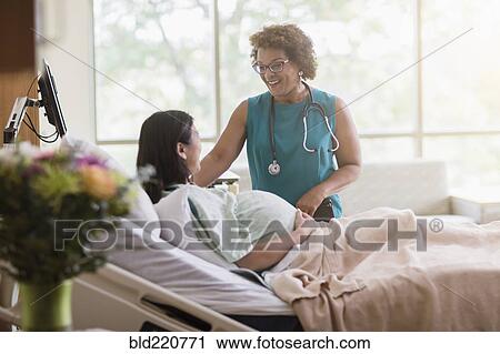 Stock Image - Doctor talking to pregnant patient in hospital room. Fotosearch